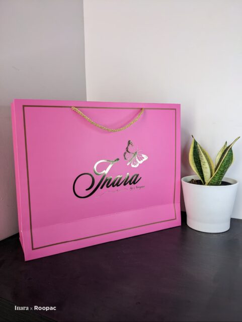 Pink foil paper bag with gold foil-stamped logo for 'Inara by Swapna', a women's clothing store in Hyderabad
