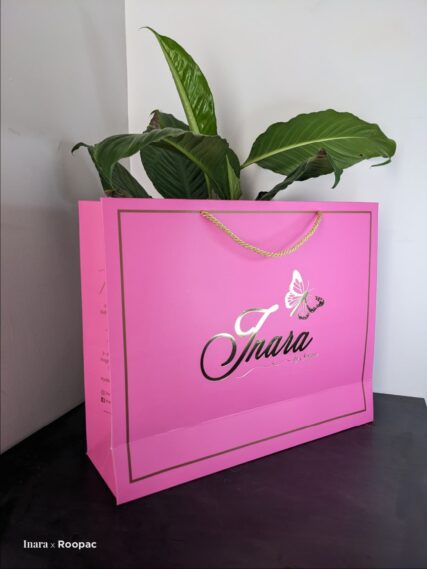 Stylish pink and gold foil paper shopping bag, custom-made for 'Inara by Swapna', a premium women's clothing store in Hyderabad.