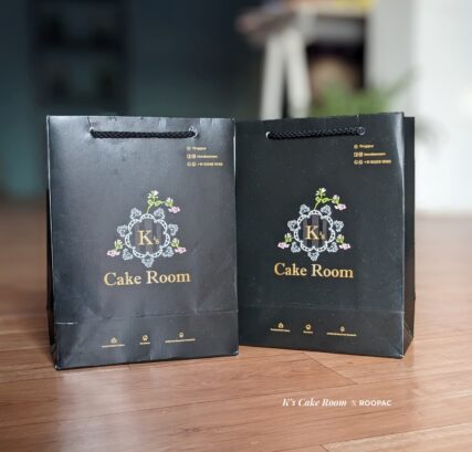 A professional-looking paper bag from K's Cake Room, designed to securely hold and protect cakes during transportation and storage