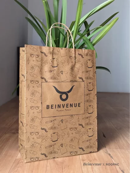 A stylish customer at "Bienvenue" Men's Clothing Store in Tiruppur holding a Roopac Durable Brown Kraft Bag.