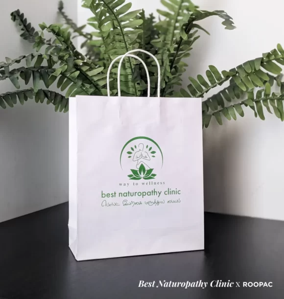 Roopac's printed paper bag held by a customer of Best Naturopathy Clinic in Coimbatore.