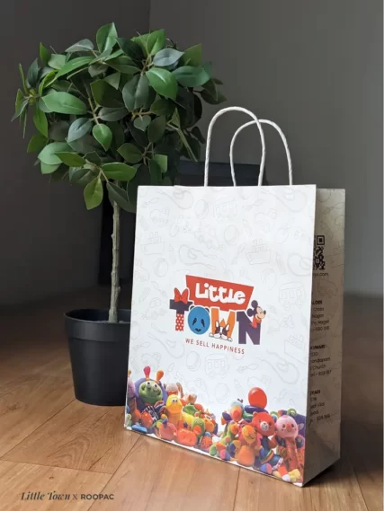 A child happily carrying a Roopac custom-printed paper bag from Little Town Toy Store.