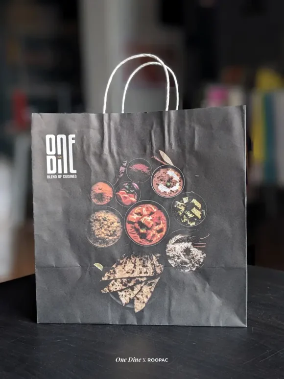 One Dine paper bag holding gourmet takeout food