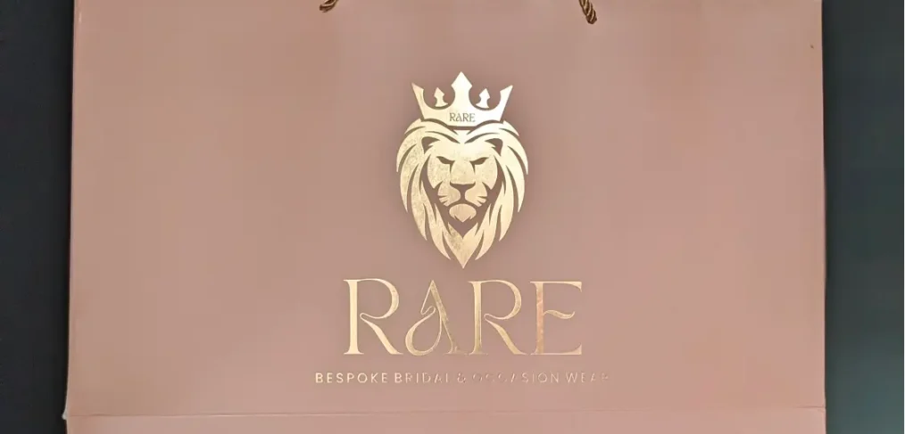 RARE's luxury gold-foiled paper bag with a lion face logo on pastel pink, Coimbatore